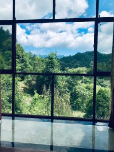 een raam met uitzicht op een bos bij Zhangjiajie one step to heaven inn (Yangjiajie ticket office) in Zhangjiajie