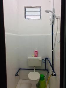 a white bathroom with a toilet and a window at Bunga Raya Guest House BALING in Baling