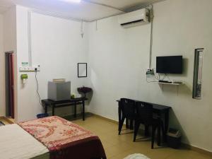 1 dormitorio con cama, mesa y TV en Bunga Raya Guest House BALING, en Baling