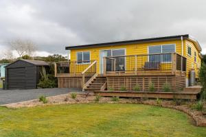 a yellow house with a deck and a yard at The Yellow House in Kaka Point