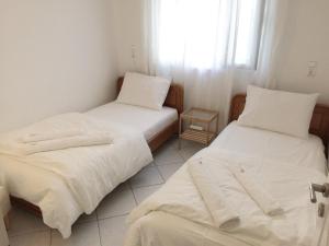 two beds in a room with white sheets and a window at Sofia’s House in Pramanta