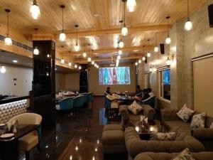 a restaurant with couches and tables and people sitting at tables at Hotel Grand Maple in Jaipur