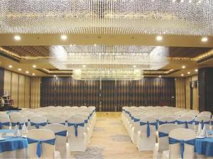 a banquet hall with white tables and white chairs at Hotel Grand Maple in Jaipur