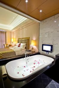 een badkamer met een bad, een bed en een televisie bij The Royal Pinnacle Hotel in Doumen