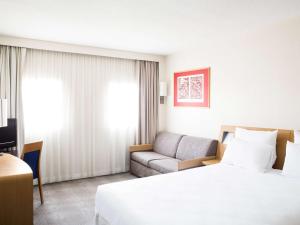 um quarto de hotel com uma cama e um sofá em Novotel Setubal em Setúbal