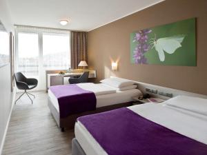 a hotel room with two beds and a desk at Mercure Hotel Hameln in Hameln