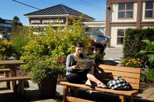 a woman sitting on a bench reading a book at Hôtel Centre-Ville in Montmagny