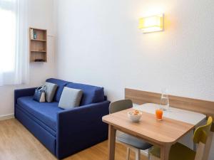 a living room with a blue couch and a table at Aparthotel Adagio Access La Défense - Place Charras in Courbevoie