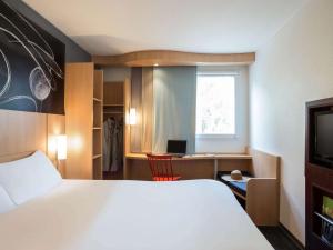 Habitación de hotel con cama, escritorio y ventana en ibis Paris Meudon Velizy en Meudon