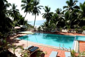 a swimming pool with palm trees and the ocean at Soma Palmshore in Kovalam