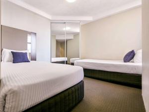 a hotel room with two beds and a mirror at Novotel Surfers Paradise in Gold Coast