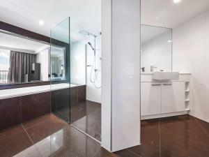 a bathroom with a glass shower and a sink at Novotel Surfers Paradise in Gold Coast