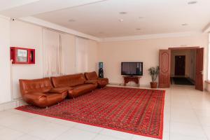 un sofá de cuero marrón en una sala de estar con una alfombra roja en GYM Inn, en Tashkent