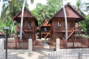 zwei Holzhäuser mit Palmen im Hintergrund in der Unterkunft Villa panrangluhu in Bira