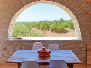 mesa y sillas en una habitación con ventana en Anaroussa Diros Maisonette, en Areopoli