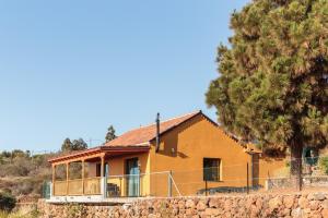 une maison jaune avec une clôture et un arbre dans l'établissement CASA LAURA el canal, à Puntagorda
