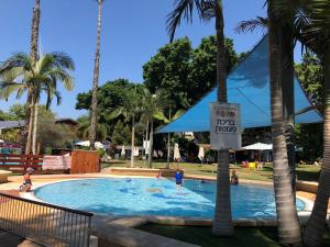 a pool with people in it with palm trees at Kfar Maccabiah Business & Sport Hotel in Ramat Gan