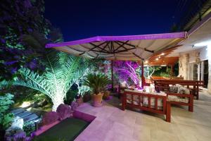 a patio with benches and a large umbrella at Apartments Villa Hraste Hvar in Hvar