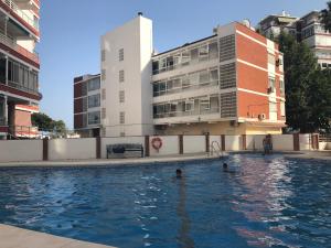 dos personas en una piscina frente a un edificio en Vistamar Beach Luxury - 1ª Línea De Playa En Torre del Mar, Piscina y Apartamiento, en Torre del Mar