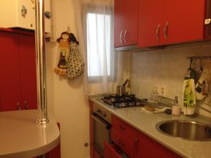 a kitchen with red cabinets and a sink and a window at STUDIO RESIDENCE PLANORAMA in Bucharest