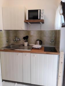 een witte keuken met een wastafel en een magnetron bij Apartments Garden in Rovinj