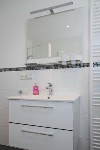 a white bathroom with a sink and a mirror at Location 1 in Rimschweiler +6 photos