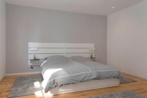 a white bedroom with a bed with a headboard at Location 1 in Rimschweiler