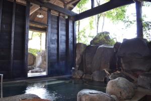 a room with a pool of water and rocks at Tabinoyado Asonoyu in Aso