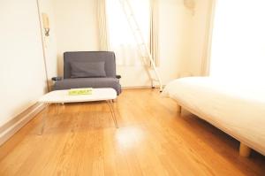 a bedroom with a bed and a chair and a table at Plusone Fujisaki in Fukuoka