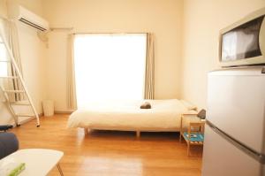 een slaapkamer met een bed en een groot raam bij Plusone Fujisaki in Fukuoka
