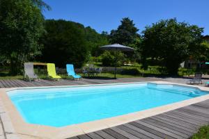 uma piscina com cadeiras e um guarda-sol em Chambres d´Hôtes Le Cèdre Bleu em Saint-Lattier