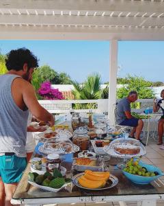 Un homme debout à une table pleine de nourriture dans l'établissement Albergo isola mia, à Favignana