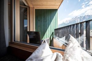 uma varanda com almofadas e vista para as montanhas em Hotel Simpaty em Dobbiaco