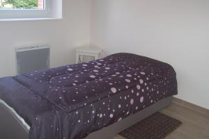 a bed with a purple blanket with polka dots at La Prairie in Saint-Pair-sur-Mer
