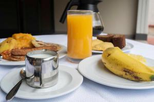 a table with plates of food and a glass of orange juice at Emmaus Guesthouse Kampala in Kampala