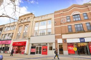 two people walking down a street in front of buildings at The Broadmead Forest - Spacious City Centre 3BDR Apartment in Bristol