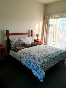 a bedroom with a bed with a blue bedspread and a window at Sunflower Self-Catering in Walvis Bay