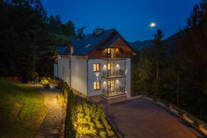 una gran casa blanca con sus luces encendidas en Willa nad Parkiem, en Szczawnica