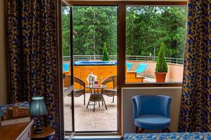 een kamer met een balkon met een tafel en stoelen bij Hotel Park Bachinovo in Blagoevgrad