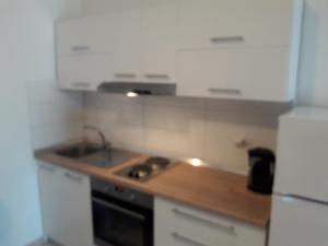 La cuisine est équipée de placards blancs, d'un évier et d'un réfrigérateur. dans l'établissement Apartments Dalmacija, à Podstrana