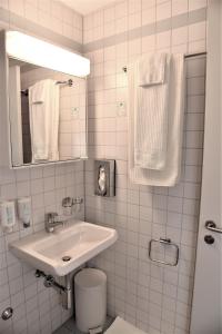 a white bathroom with a sink and a mirror at Hotel am Spisertor in St. Gallen