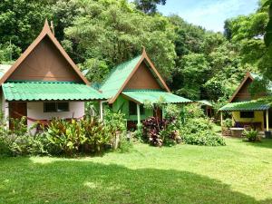 a house with a green roof in the grass at TP Hut Bungalows in Ko Chang