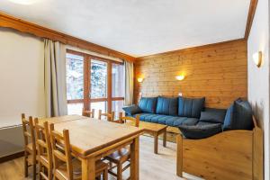 a living room with a blue couch and a table at Quartier La Forêt - maeva Home in Valmorel