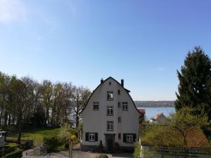 ein großes weißes Haus mit einem See im Hintergrund in der Unterkunft Gunkel Ferienwohnungen am See - Konstanz - Musikerviertel in Konstanz