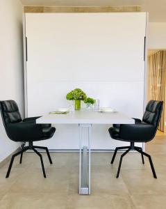 a white table with two chairs and a white wall at Blue City Apartments in Lübeck +32 photos