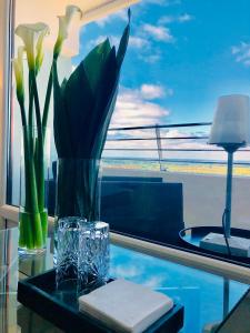 einen Glastisch mit einer Vase aus Blumen und einem Fenster in der Unterkunft Blue City Apartments in Lübeck