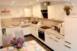 a kitchen with white cabinets and a table with flowers at Ferienwohnung Villa AusZeit in Königstein an der Elbe