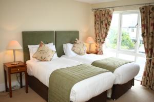two beds in a hotel room with a window at Castle Oaks House Hotel in Limerick
