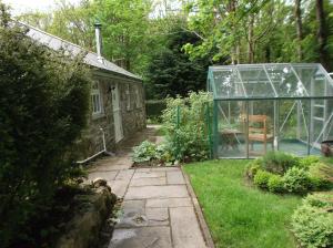 a greenhouse in a garden with a chair in it at new pottery in Penzance