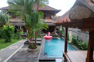 a swimming pool in front of a building with a house at Ubud Sensasi Bungalow in Ubud